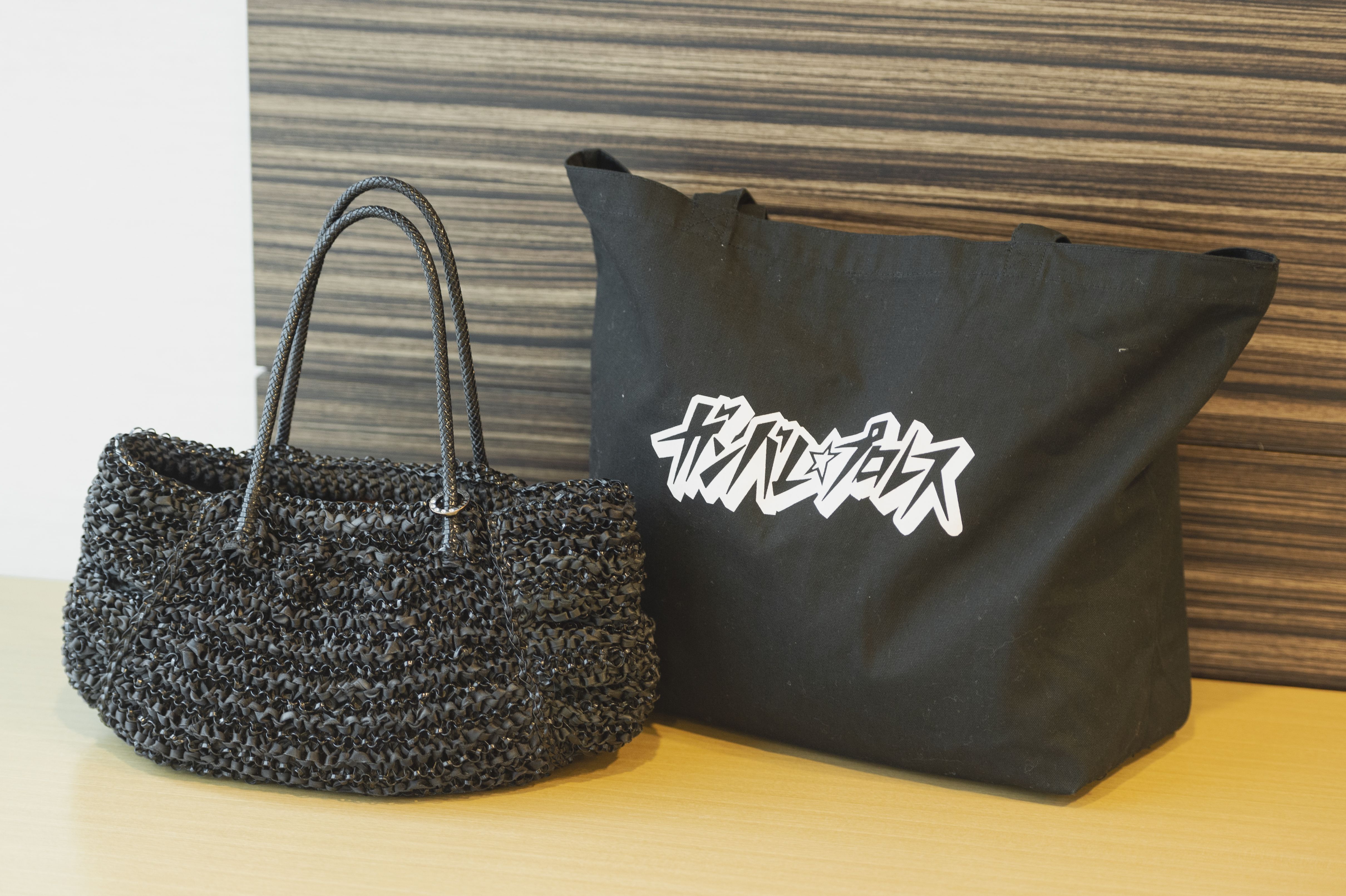 堀井さんが愛用しているアンテプリマのバッグ（写真左）。隣のトートバッグは、盟友ジェーン・スーさんのご贔屓でもあるインディーズプロレス団体「ガンバレ☆プロレス」のオフィシャルグッズ