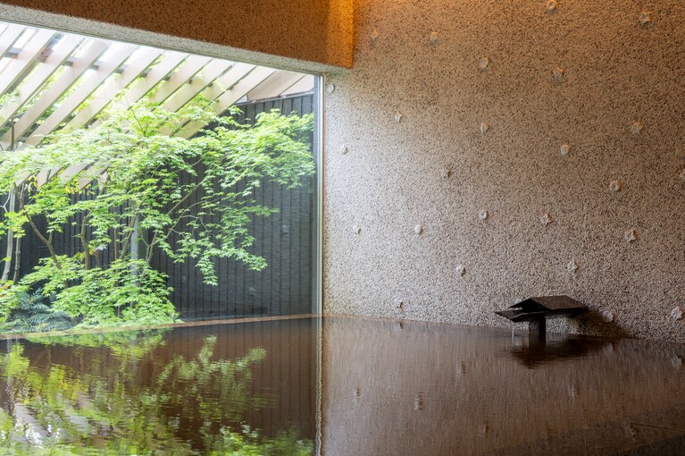風情ある温泉大浴場。壁面には、鶴見岳と由布岳の花々をモチーフにした臼杵焼が。