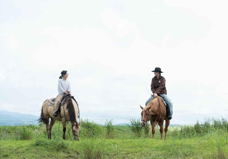 囲いのある馬場だけではなく、阿蘇五岳や九重連山を眺める大地まで足を延ばす、ダイナミックな乗馬体験。