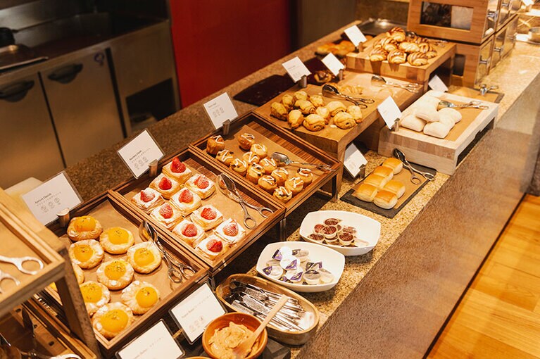 ペストリー、クロワッサン、全粒粉ブレッドなど多彩なパンが並ぶ。