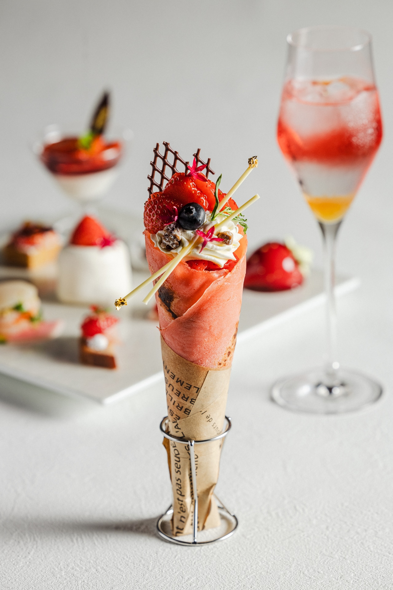 スペシャリテ「いちごティラミスクレープ」のイメージ。ピンク色のクレープ生地に、芳醇なバニラが香るティラミスクリーム、みずみずしいいちごとコンフィチュールを重ねた、味わいも見た目も華やかなひと品。