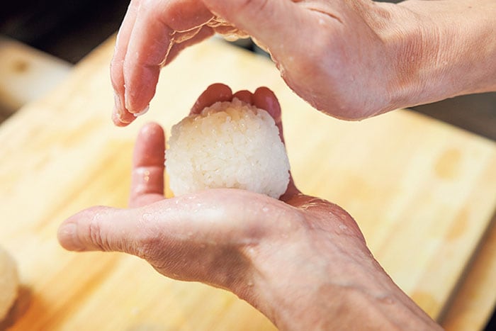 三角ににぎるときは、まず手の平にご飯をふんわりのせ、もう一方の手は山形にして軽くにぎる。