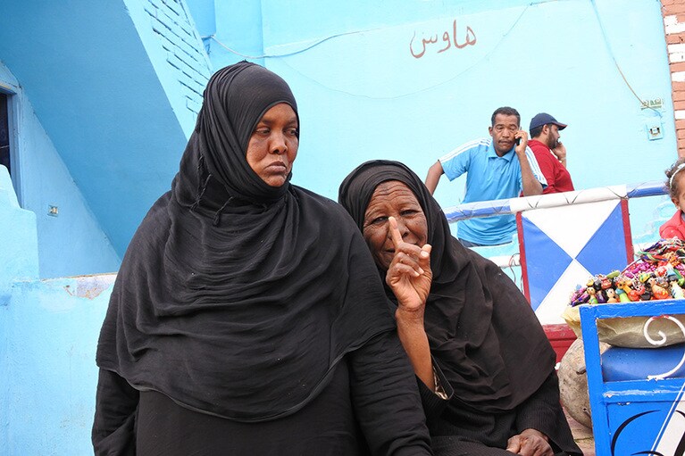 イスラム教の服をまとったヌビアの女性。カラフルな村の中で黒が目立つ。