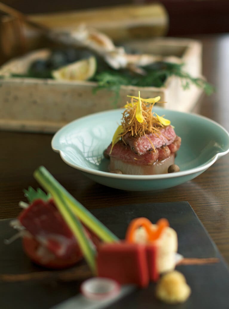 名物の3品。手前から馬刺、阿蘇あか牛ステーキ、山女魚塩焼き。ステーキの下は特産の小国大根。上には細く切って揚げた“髭牛蒡”と菊花をのせ、周りに零余子（むかご）を散らして。