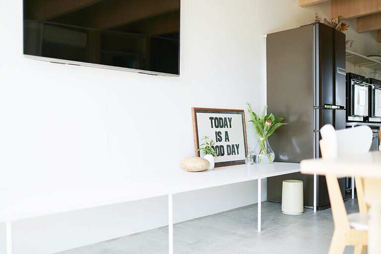 壁掛けのテレビの下には白い台が。人が集まったときのベンチにしたり荷物置き場にしたりと多用途。