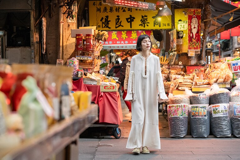 色とりどりの街の中で映える白のロングワンピースの足元には、やさしい色合いのユニーク（ミモザ2）を合わせて。寒暖差が激しいこの季節、少し肌寒く感じたらソックスを合わせるのもかわいい。色のトーンを合わせるもよし、あえて外した色を選んでアクセントにするのもこれまたよし。ソックスとのコーディネートを楽しめば春から秋まで長い季節活躍してくれるのもユニークシリーズの魅力。UNEEK 14,300円／キーン（キーン・ジャパン）、ワンピース 74,800円／フミエタナカ（ドール）、その他／スタイリスト私物