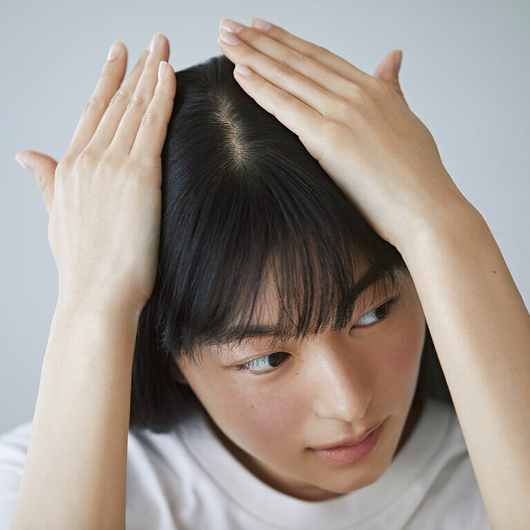 【オイル＆バームのダブル使いスタイリング STEP⑤】頭頂部を押さえるようになじませる。その後、指で整えながら浮き毛を押さえる。
