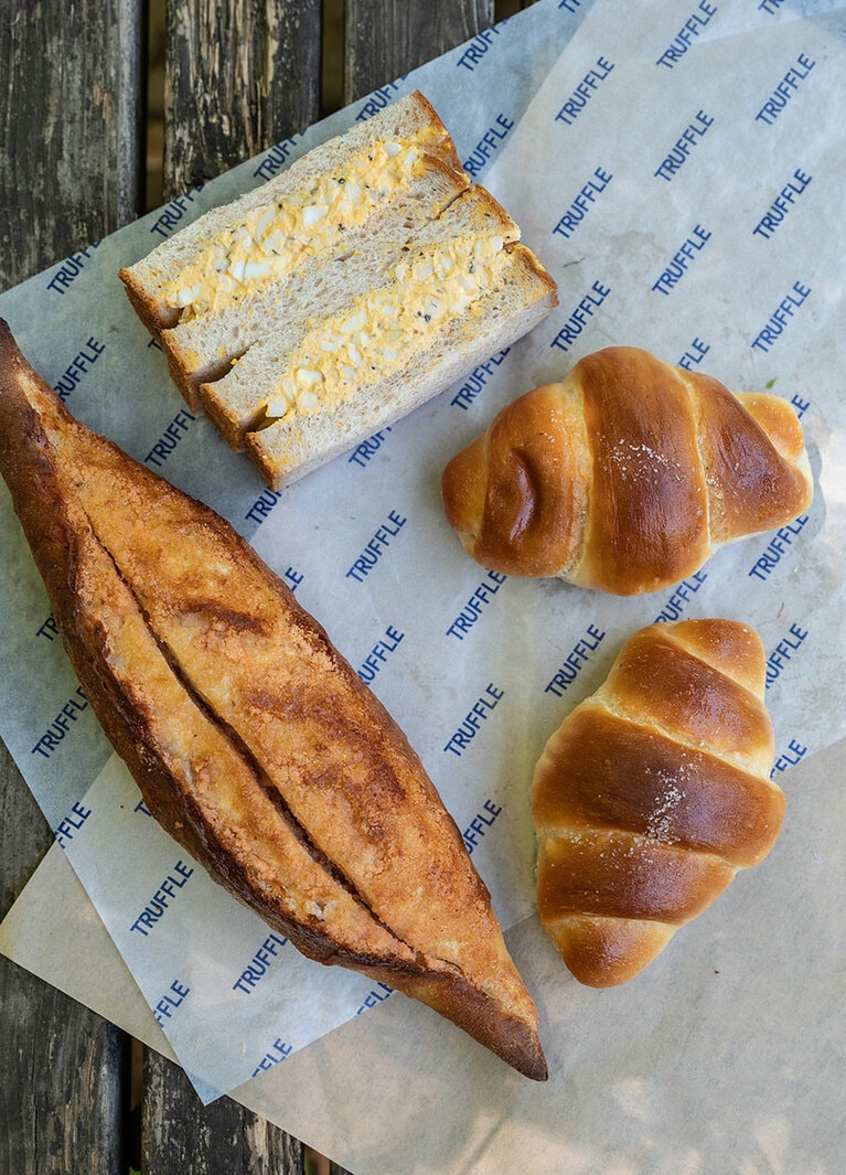 左から、「稚加栄の明太フランス」734円、「黒トリュフのタマゴサンド」626円、「白トリュフの塩パン」1個 194円。