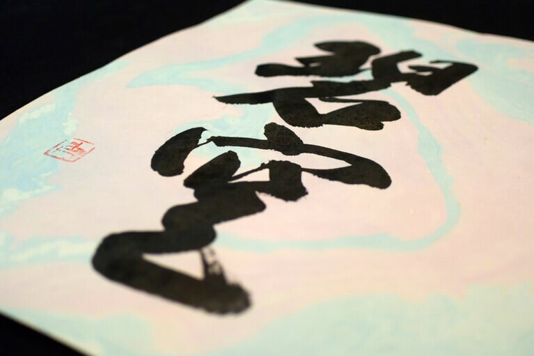 墨流しと、書家の角谷有紀さんの書が調和した作品。