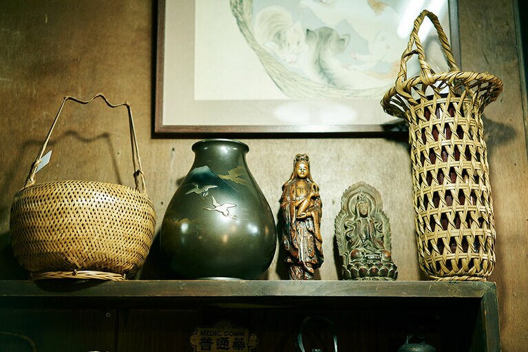 カゴの花入れの横に仏像など、ランダムにアイテムが並ぶ。棚の端っこにお宝があるかも！