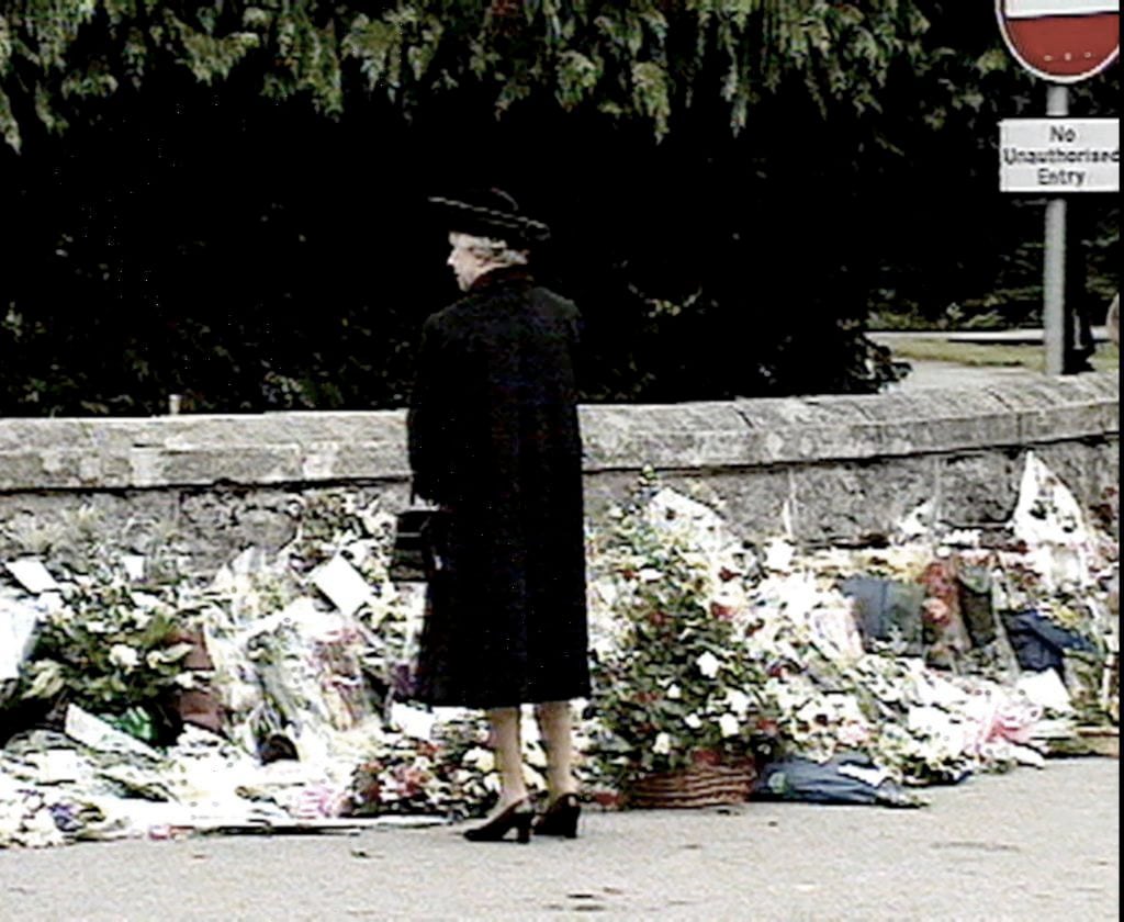 1997年9月4日、故ダイアナ元皇太子妃にささげられた花束や弔辞に見入るエリザベス女王　©AFP＝時事