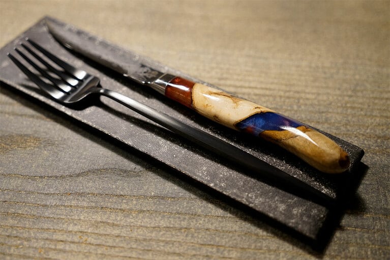 高村刃物製作所のナイフ。地元利賀村の木を組み合わせ、隙間に自然の色を表現した樹脂を流し込んで成型したもの。肉に吸い込まれる切れ味と、細部へのこだわりが料理の味を引き立ててくれる。