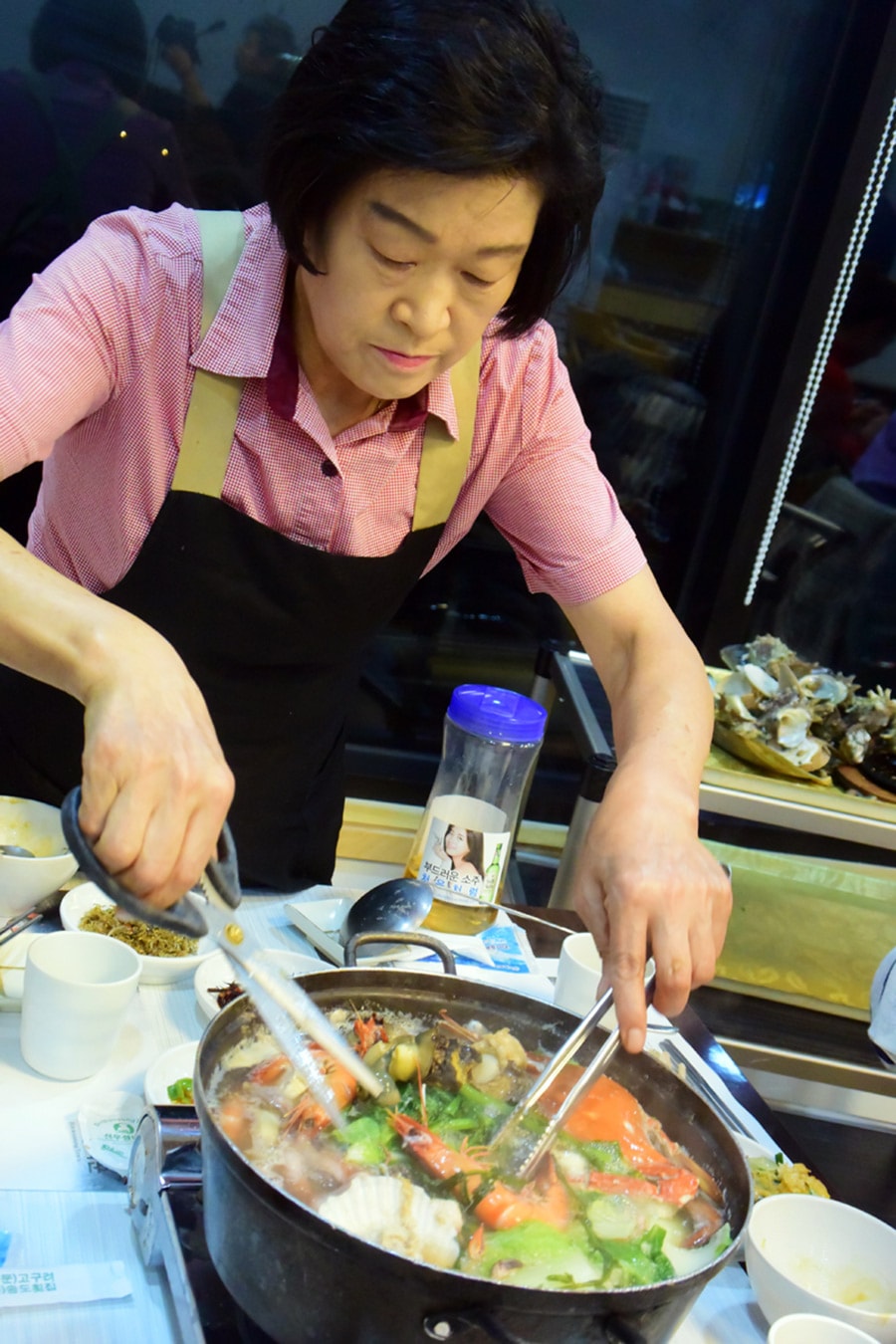 海鮮鍋を食べやすいように、スタッフが具材をはさみでチョキチョキ。この手際の良さ、骨付きカルビと共通するものが。