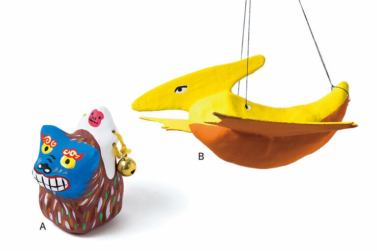 A：シーサーの背に猿がまたがる〈獅子乗り猿〉2,200円。  B：お部屋の天井にぶら下げて楽しみたい、恐竜張り子〈プテラノドン〉1,250円。