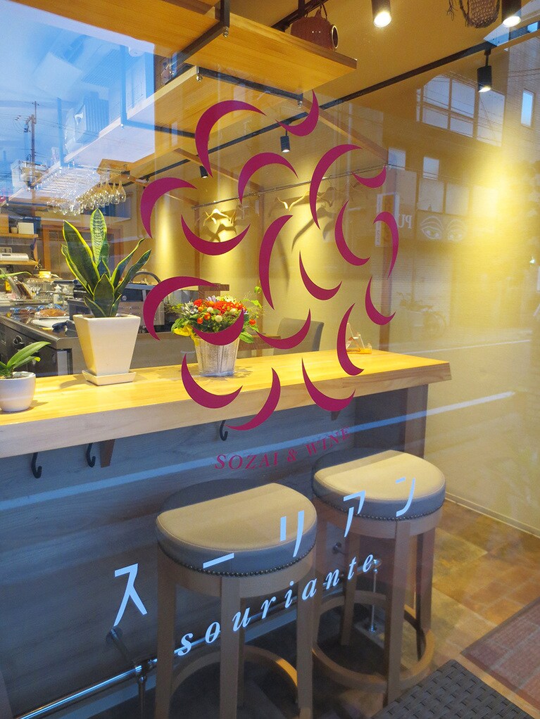 ガラスに描かれた店名のロゴと笑顔のマーク。