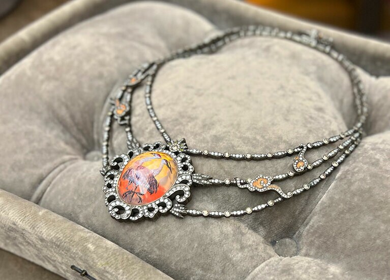 ネックレスのペンダントトップに2羽の鶴が片足立ちしている。