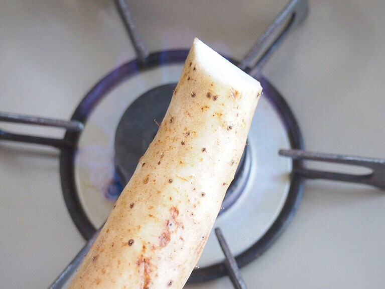 (2) 野菜の下処理をします。長芋は表面を洗ってひげ根をガス火で焼き切ります。