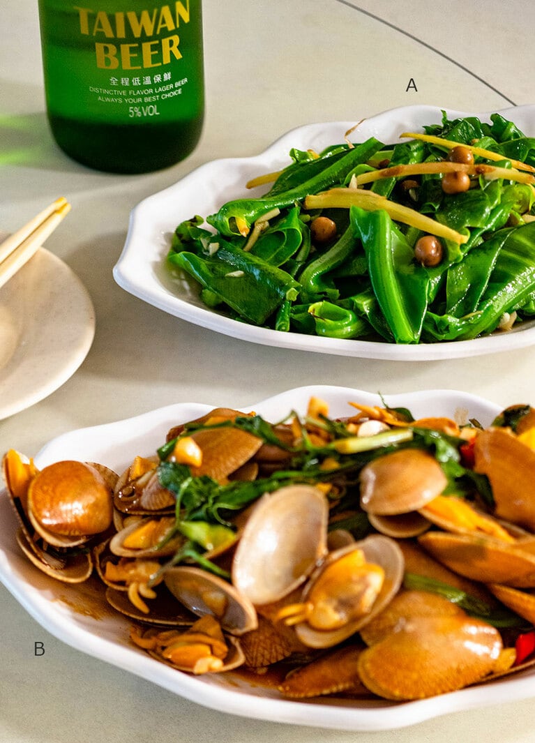 A：シマオオタニワタリの炒め物「樹子炒山蘇(シュズーチャオシャンスー)」280元。破布子(樹子)と呼ばれる木の実とショウガで炒めたもので箸休めに。 B：ヒメアサリの醬油炒め「塔香海瓜子(ターシャンハイグァーズ)」320元。台湾産バジルとニンニクの風味が抜群。ビールに合う！