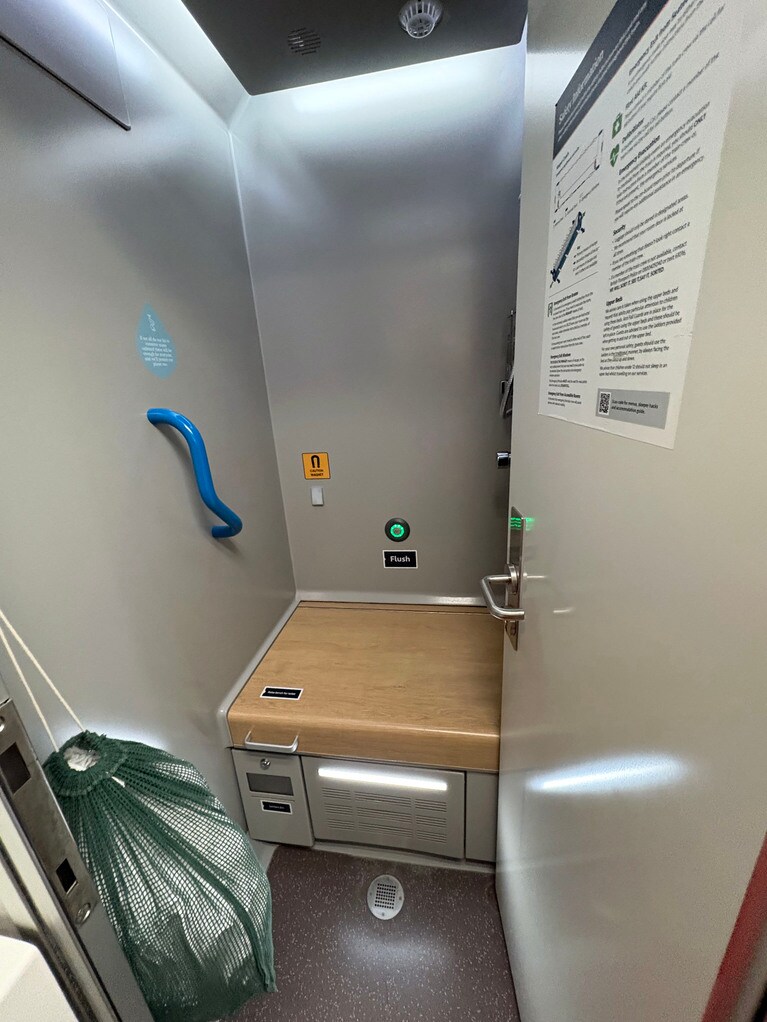 木のボードを上げると便座に。右にハンドシャワーが。