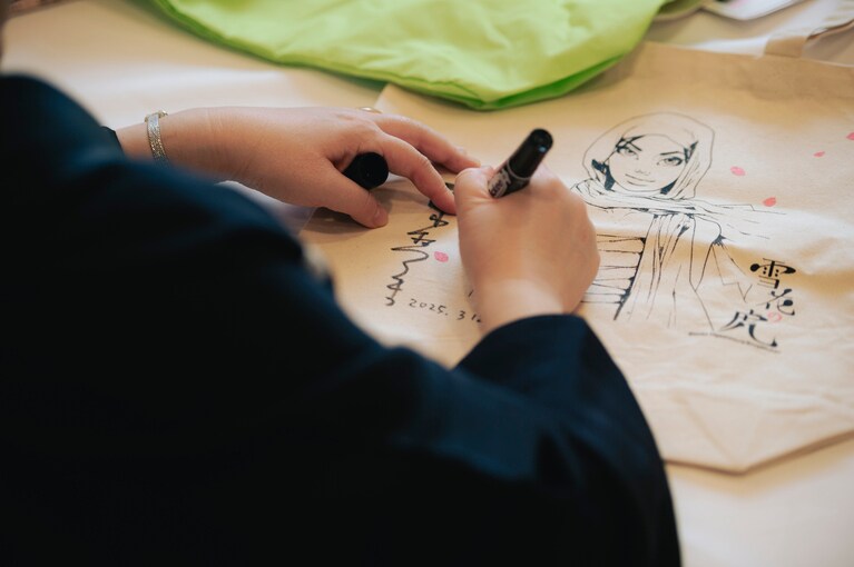 『雪花の虎』のトートバッグにサインを入れる。