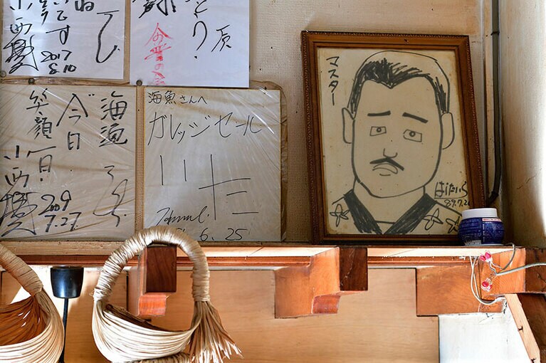 壁に飾られたたくさんの色紙のなかには、マスターの似顔絵も。