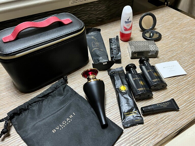 アメニティはイタリアの高級ブランド「ブルガリ」。ポーチの中に入っている黒い袋には、おしぼり、フェイスエマルジョン（乳液）、ボディエマルジョン、リップバーム、そして、オーデコロン「ルビニア」。ほかに、歯ブラシ、ヘアブラシ、ロールオンデオドラント、鏡、ティッシュが入っている。