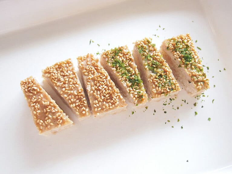 (7) 粗熱が取れたらバットから取り出し、羽子板の形になるように切ります。半分に青のりを振りかけます。