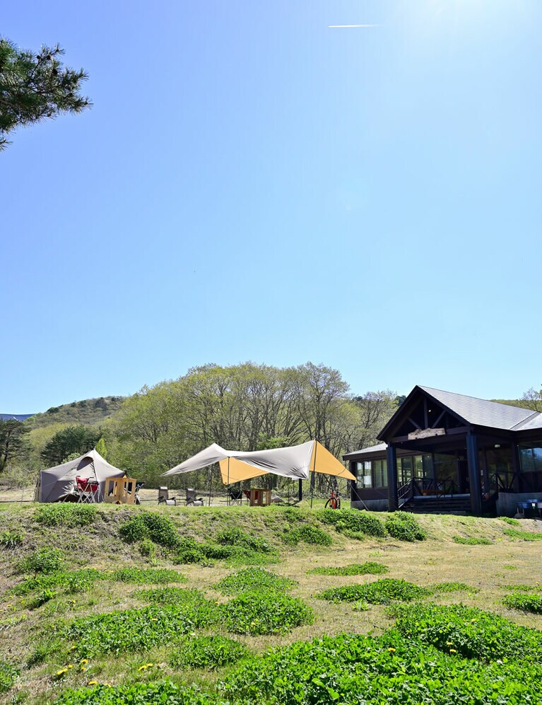カフェの目の前の芝生広場。キャンプ利用のない日は、テントの中でごろんと寝転んでもいいし、タープの下で高原の風を感じるのも素敵。Wi-Fi完備でアウトドアワーケーションも。