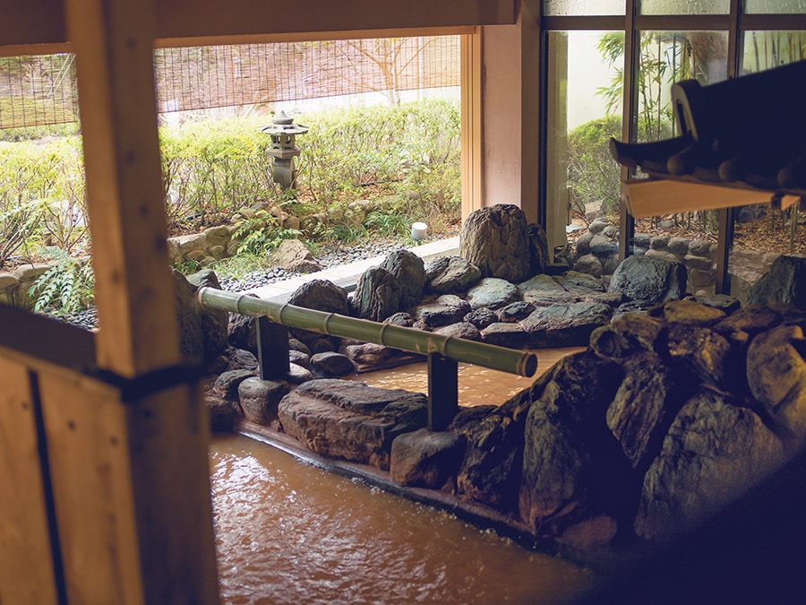 【陶泉 御所坊】源泉かけ流しの大浴場「金郷泉」。手前は男女の仕切りがしっかりあり、庭に近づくと男湯と隣り合わせになる半混浴式。Photo: Tamon Matsuzono