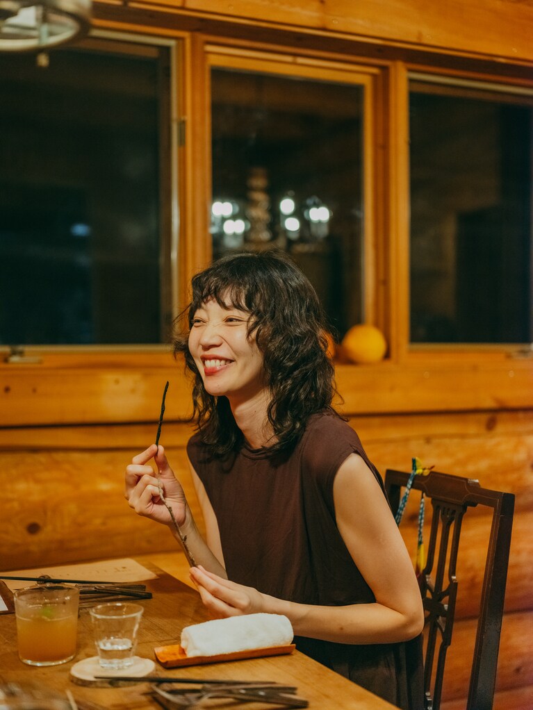 初めて食べる松の葉のスティックの新食感に思わず笑顔。「お土産話のネタにいいかも、程度に思って口の中に入れると、フワッと広がる松の香りとスナック菓子のような口当たりに驚きます。すごく美味しい！ 確かに只見の森の景色が頭の中で広がります」（星野さん）お酒にも合います。