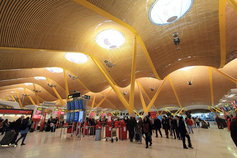 出発ロビー。外光が差し込んで波打つ天井と黄色の支柱を際立たせている。