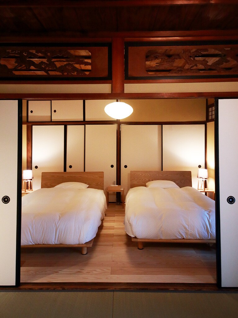 KINOE103号室のベッドルーム。通り庭を臨む縁側や欄間など、当時の面影が色濃く残る客室。板間から和室までが一間続きのゆったりとした部屋。