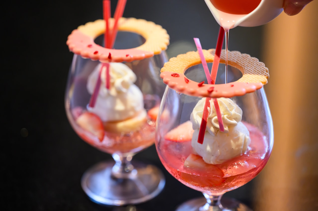 ピンクのシロップをかけて、あまおう、アイスクリーム、生クリームの調和を楽しむミニパルフェ「あまおうとチーズケーキのパルフェ」のイメージ。