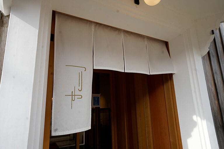 入口にかけられた暖簾。右が短くなっているのは、「右肩上がり」という縁起をかついだスタイル。商人が行き交った町ならではだ。