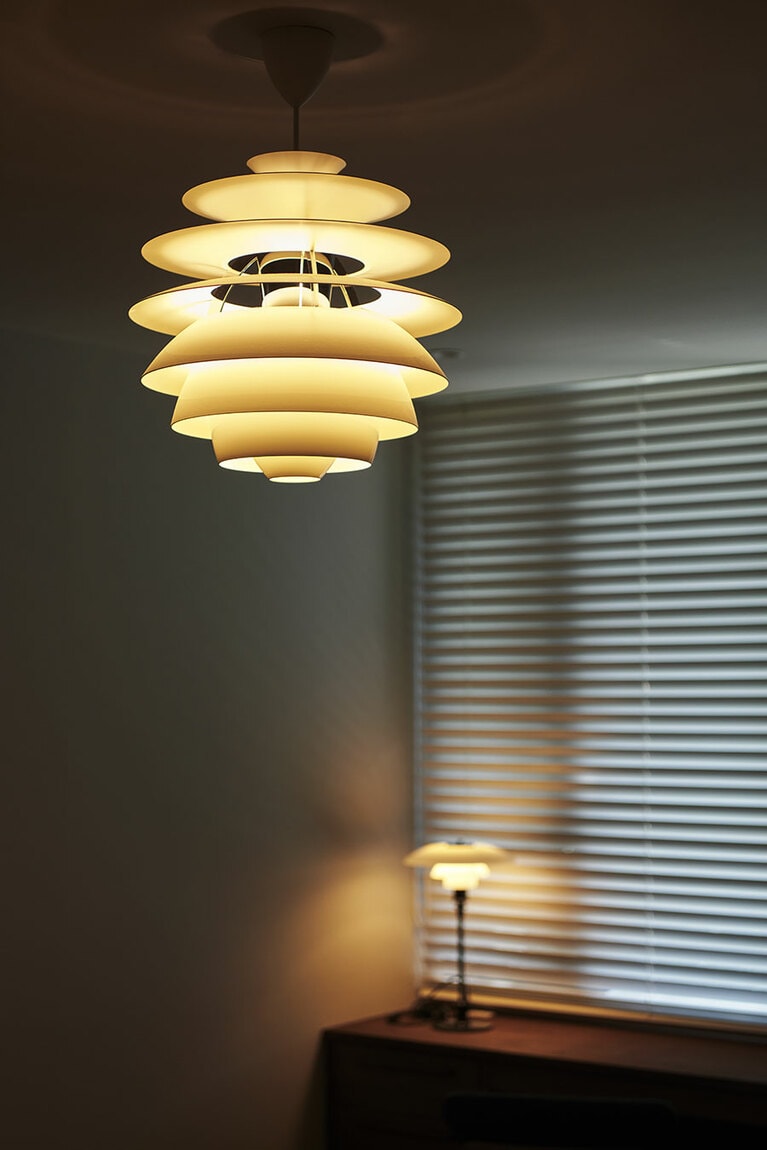 寝室のペンダントライトは短めに吊るすことで、ベッドに横になったときも目にさわらないよう配慮。窓辺のブラケットライトのやわらかな光も加わり、一日をリセットする心落ち着く空間に。