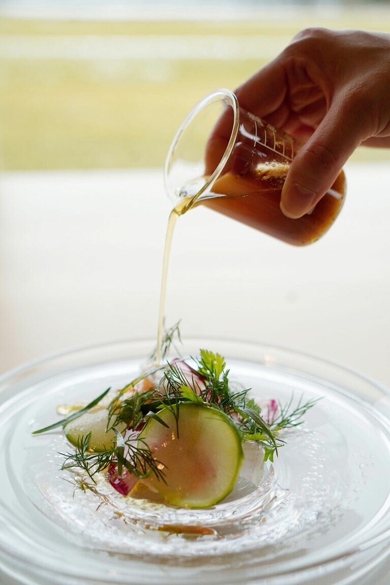 氷見の寒ブリのタルタルには、たっぷりの色鮮やかな大根などの野菜とハーブ。セロリオイルとゆず酢のドレッシングで。ドレッシングの容器がビーカーなのは製薬会社ならでは。身体が喜ぶ一品だ。