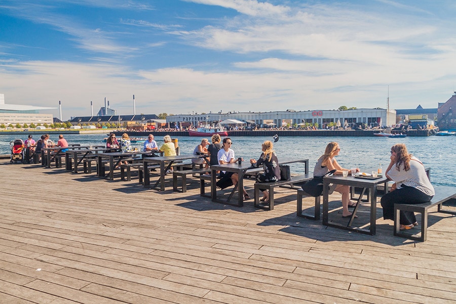 海辺のカフェでのんびりヒュッゲを楽しむコペンハーゲンの人々。2週間の旅の期間中、いろいろなところで幸せのヒントに出会えます。Photo: Matyas Rehak/123RF
