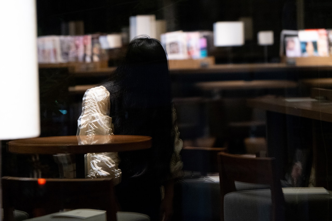 窓に写り込む野村さん。