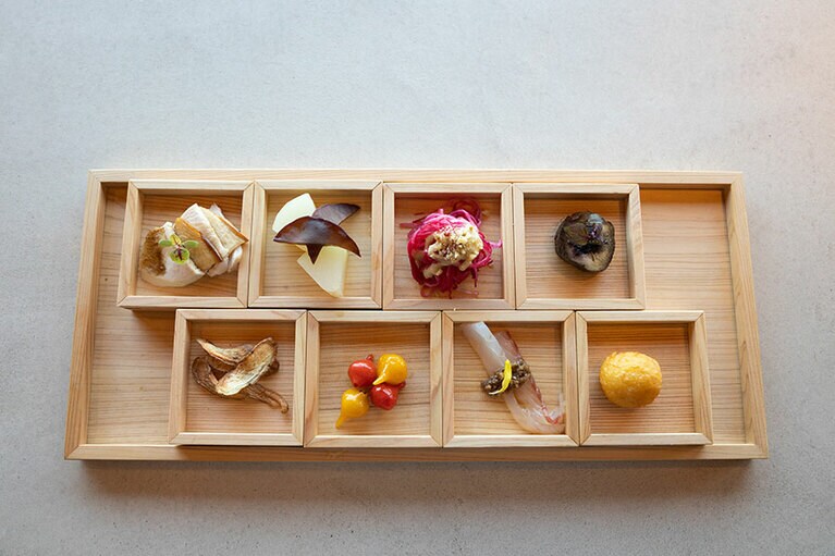 ランチコースは6,000円と8,000円のコースの2種類。メニューは季節により内容が変わる。写真は秋の前菜の八寸。左上から、『女鹿平のあわび茸』自家製鶏ハムとコーヒーソース、『尾道の青パパイヤ』生きくらげと共にコンポート、『東広島のビーツ』 青葡萄とブルーチーズのソース、 『秋茄子』ローストし自家製ゆかりと共に、左下から『牛蒡』 クミンを効かせたチップスに、『三原のビキーニョ』ピクルス仕立て、『地元の真鯛』自家製カルパッチョソースと共に、『三原のじゃが芋』シュー生地と合わせてフリット。