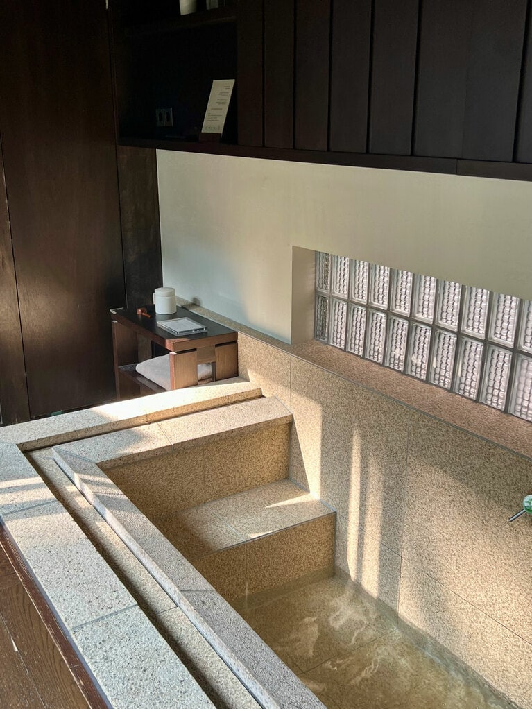 仕切りが一切なく、部屋とシームレスにつながっている大胆な浴槽。ひとりだと躊躇なく入れる。中庭が望めて日差しも心地よい。