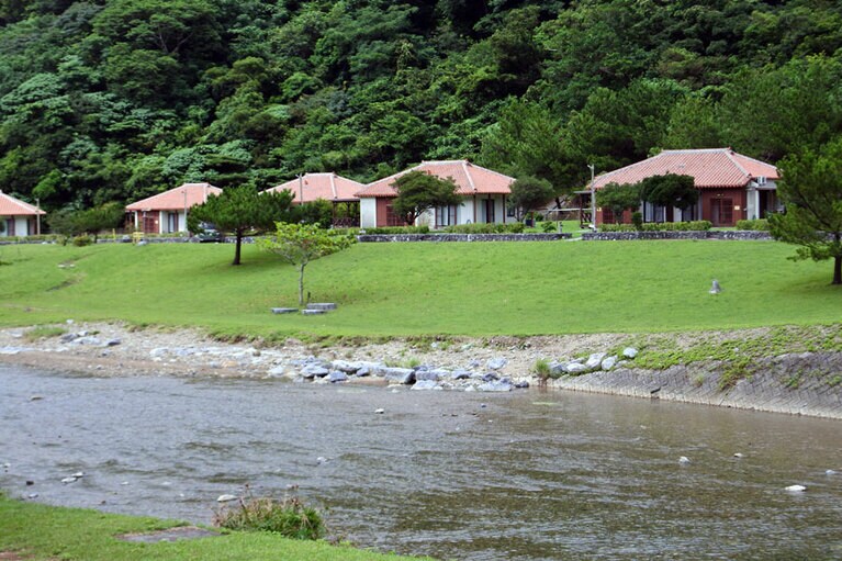 奥川のほとりに6室の沖縄民家風のコテージが並んでいます。