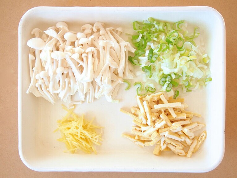 (1) しめじは固い部分を切り落として房に分けます。長ネギは粗くみじん切りにし、生姜は皮をむいて千切りにします。油揚げは、食べやすい長さの千切りにします。