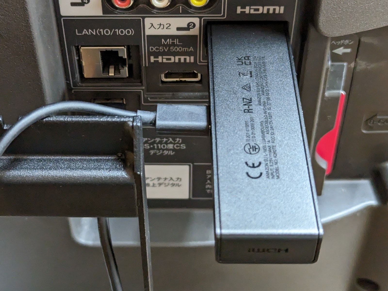 「Fire TV Stick」をテレビ背面のHDMIポートに接続した様子。給電ケーブルが真横に伸びるので取り回しはあまりよくありません