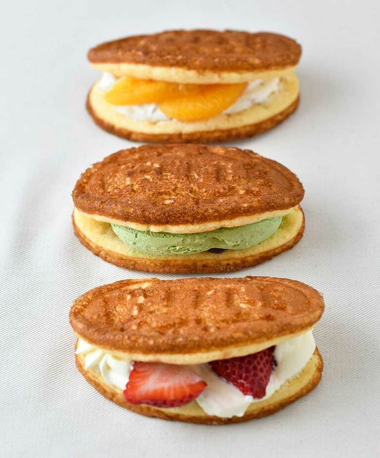 【名月堂】手前から「苺ワッフル(カスタード&ホイップ)」180円、「抹茶金時ワッフル」150円、「オレンジヨーグルトワッフル」160円。