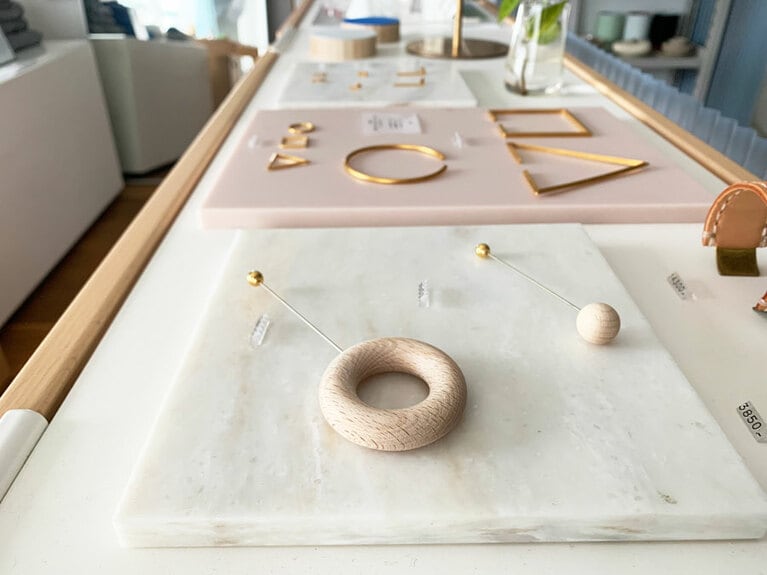 アクセサリー類もあり。手前の左はウッドブローチ RING形 8,000円、右はBALL形 6,000円。日本ブランド「_Fot(フォート)」のもの。