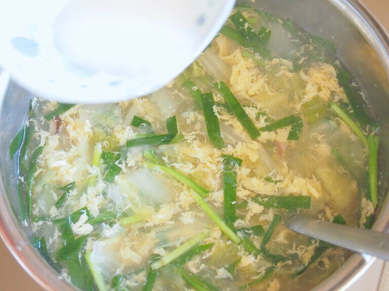 (7) ニラを入れたら沸騰させ、溶き卵を入れ、すぐに火を弱火にします。水溶き片栗粉を回し入れ、スープにとろみをつけます。