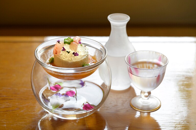 花巡りの旅にふさわしい、花びらをあしらった前菜。トマトウォーターのジュレと甘エビの昆布締めをのせ、ビスクソースでいただく「佐渡産の根菜のムース」。