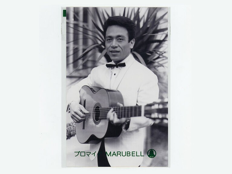 アイ・ジョージのさんのブロマイド。くっつきそうな眉毛、少し高めのギターの位置、細い蝶ネクタイ、樹木とアイ・ジョージさんの頭部との重なり具合など、構図の美しさが見事だ。