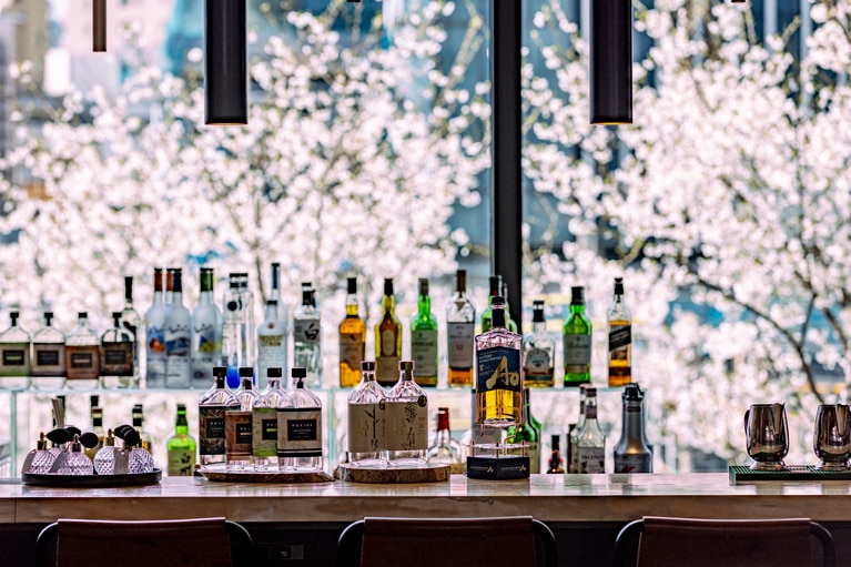 柔らかな灯りに照らされた桜がバーカウンターの窓一面に広がり、春の夜にふさわしい落ち着いた雰囲気を演出する。ライトアップは、2026年3月27日（金）～4月10日（金）の約2週間限定で実施予定。（※桜の開花によって変更の可能性あり）
