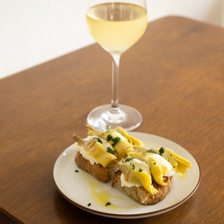 定番の「アーティチョークとリコッタチーズのブルスケッタ」（750円）はワインのいいお供。合わせたワインはサルデーニャ島の白（グラス800円）。